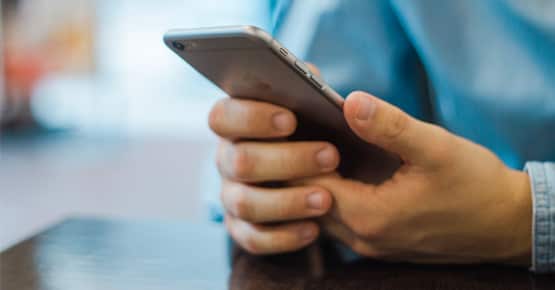 man looking at mobile phone and could be receiving guest messaging from a hotel